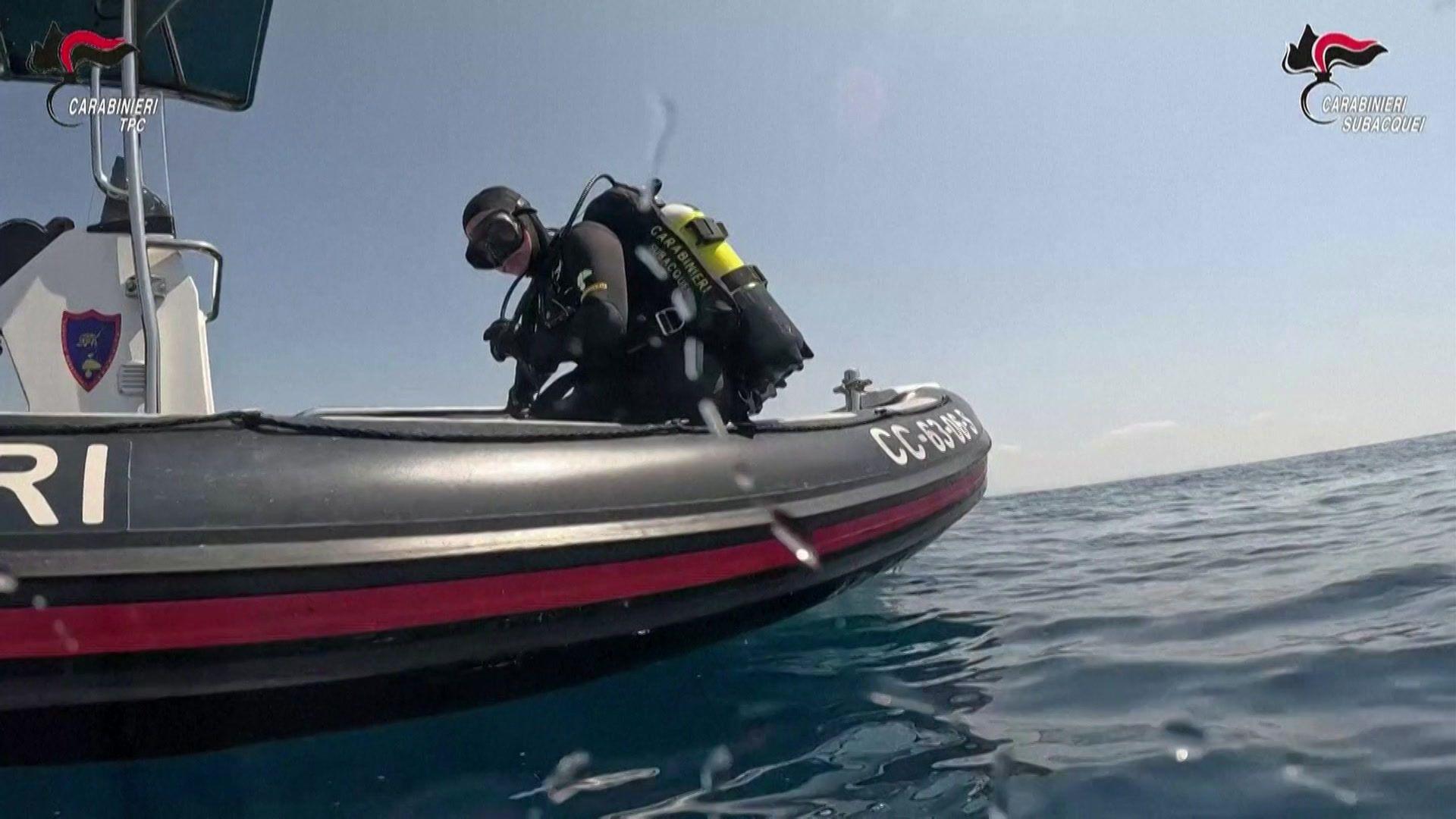 A diver in full scuba gear on the edge of a small boat in the sea