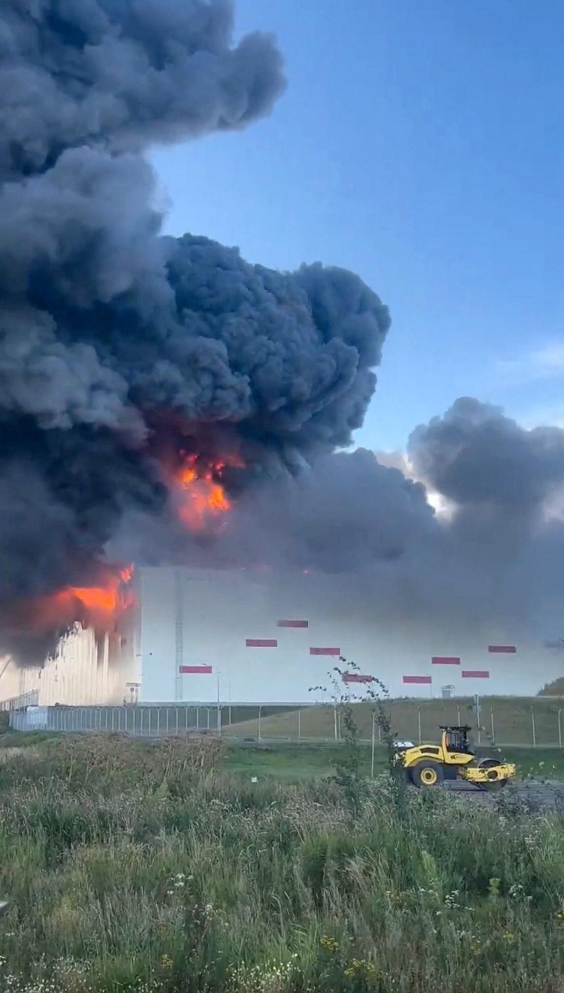 Huge flames and black smoke rise from a warehouse with similar design to other Wildberries warehouses