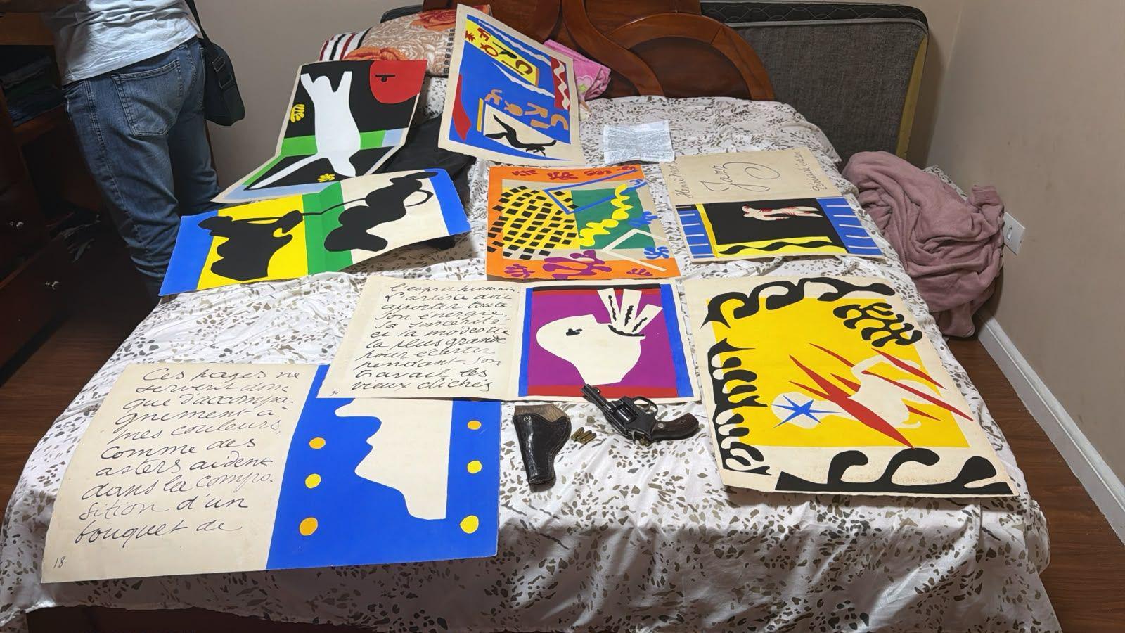 The Matisse illustrations - bold cut out collages in primary colours and black - are pictured laid out on a bed, alongside a handgun
