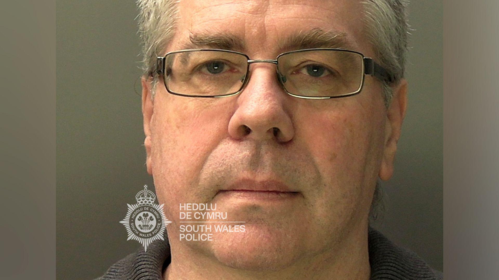 A mugshot of Christopher Phillips, who has grey hair and glasses