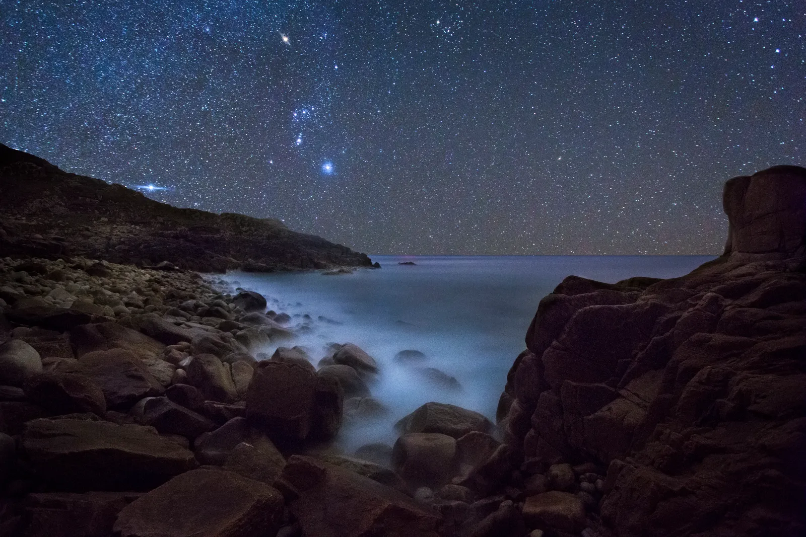 Image may contain Rock Nature Night Outdoors Scenery Beach Coast Sea Shoreline Water Starry Sky and Sky