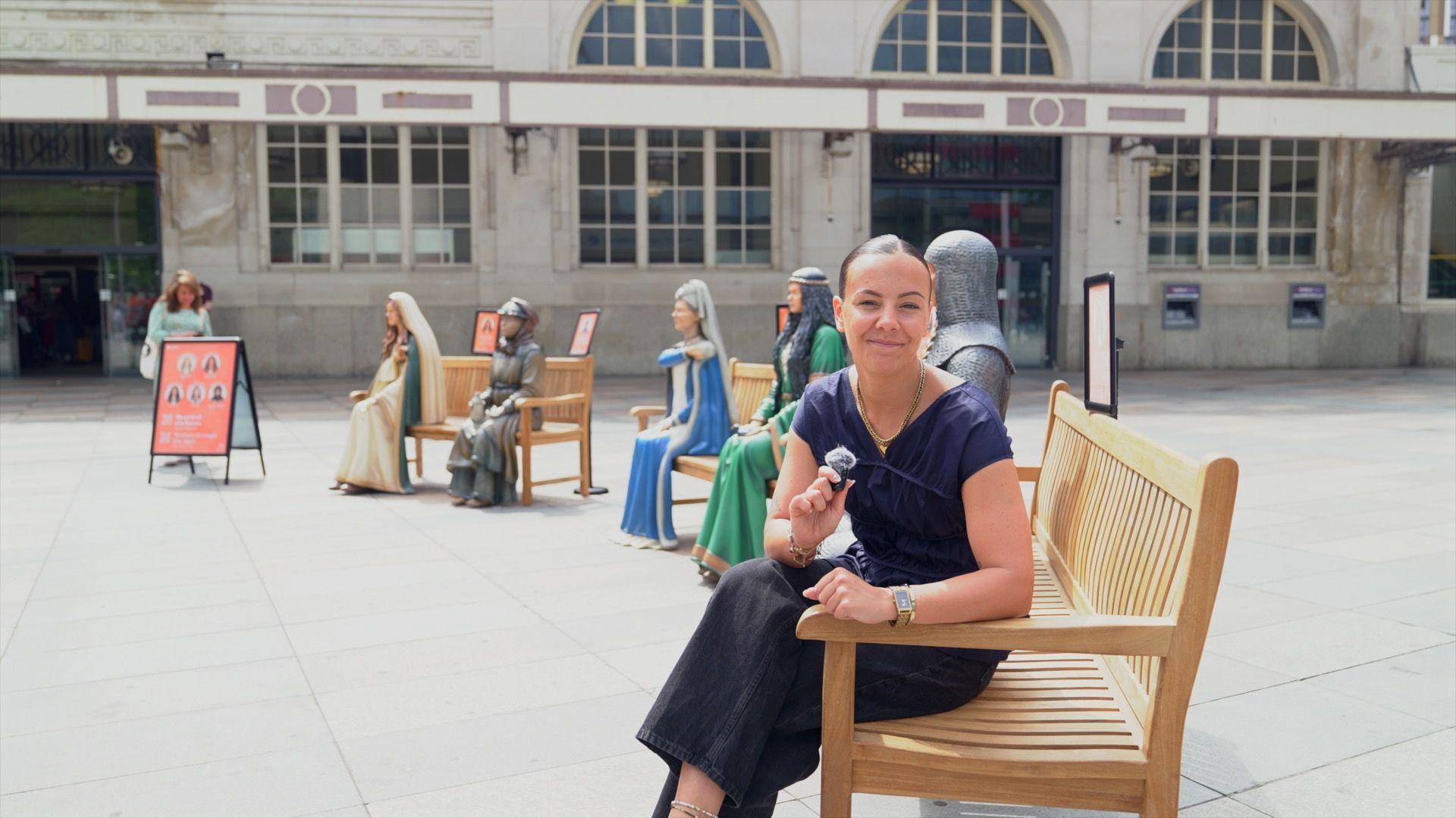 Tink Llewellyn sat on a bench with five statues of Welsh women behind her
