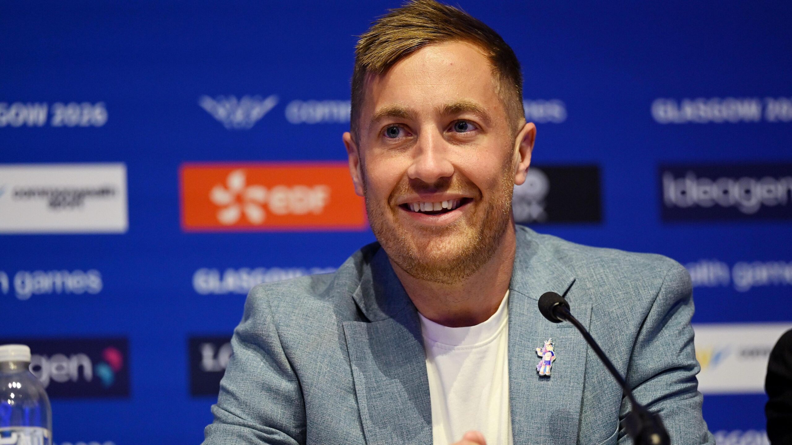 Phil Batty smiling. He is in a blue jacket and white T-shirt and has blonde hair.