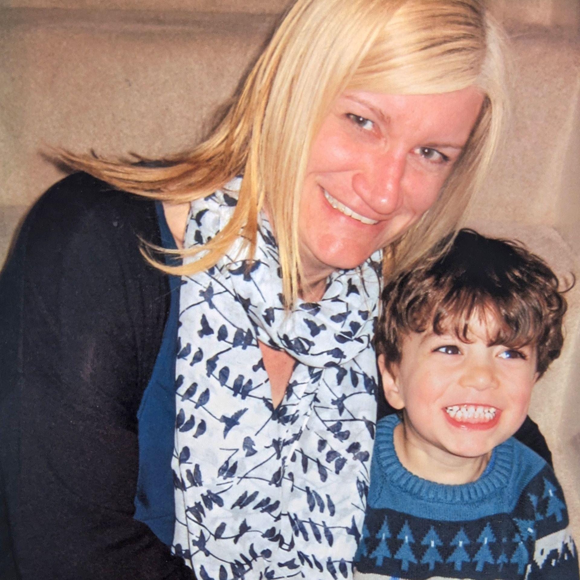 Rachel and her son Jonah both hugging and smiling. Rachel has light hair and blue eyes, Jonah has dark hair and brown eyes, they are both wearing blue tops.