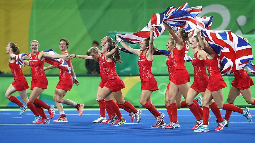Team GB hockey players run with Union Jacks as they celebrate their hockey gold in 2016
