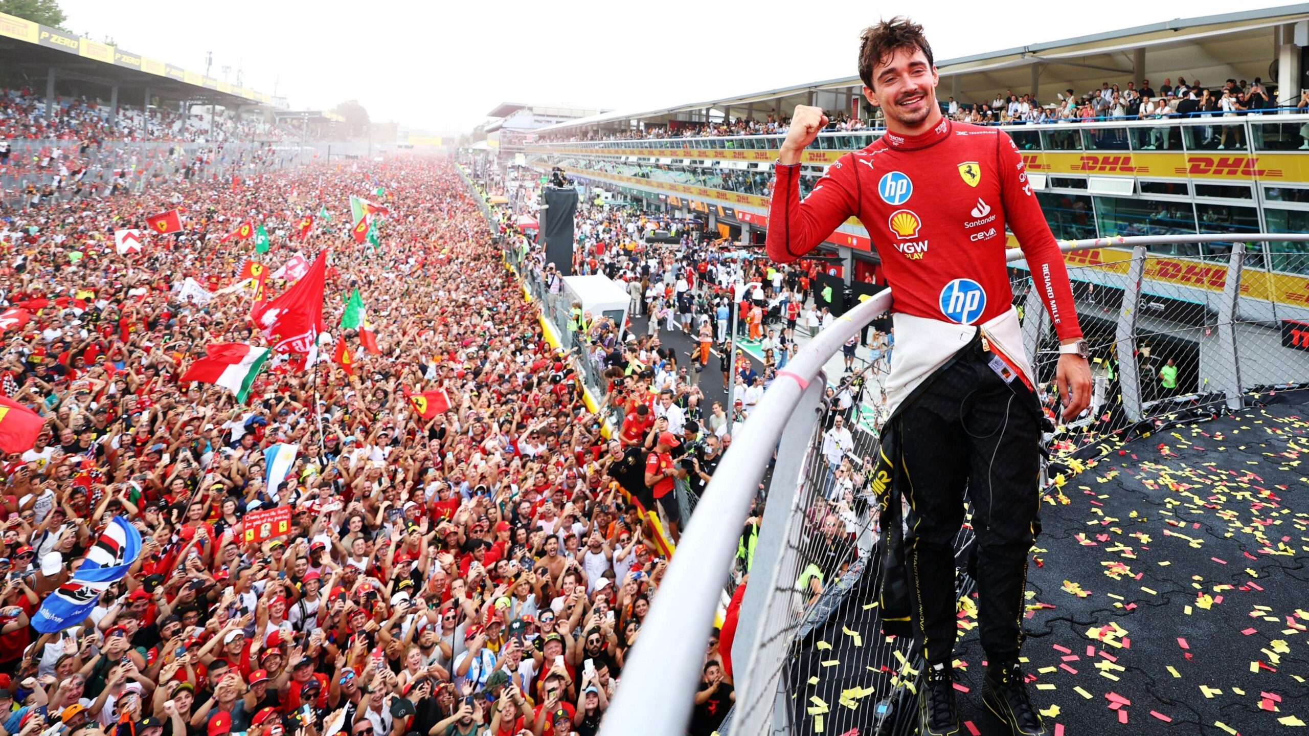 Race winner Charles Leclerc, of Ferrari, who is stood on the podium, smiles and points towards the Italian 'tifosi' fans, who are gathered on the track, celebrating his victory in 2024