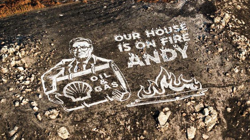 A Greenpeace mural Andy Burnham in white paint on a scorched hillside