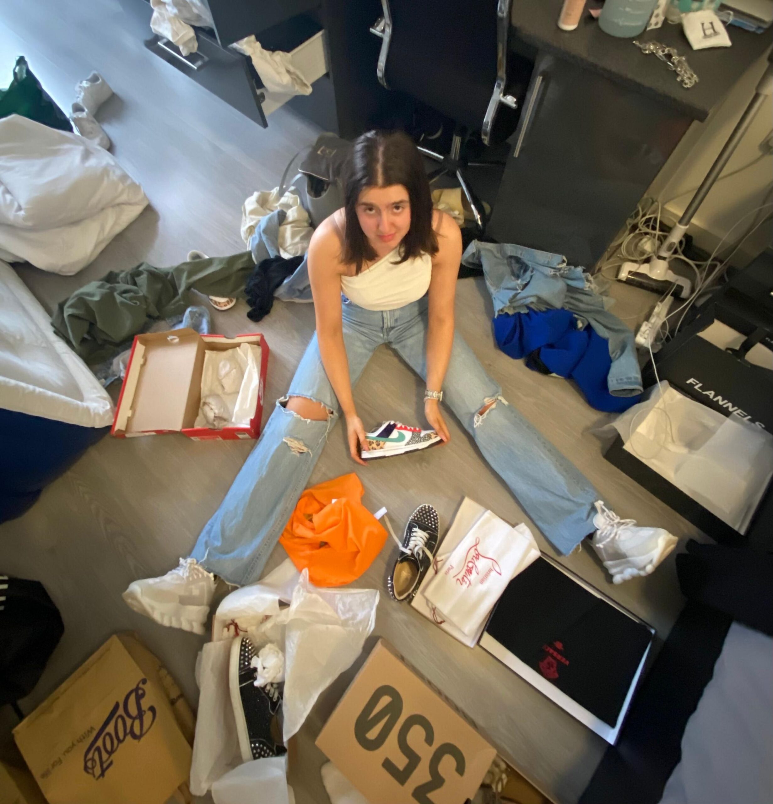 Ella Hewitt sits on her bedroom floor, looking sad. She is surrounded by fashion and shoe boxes.