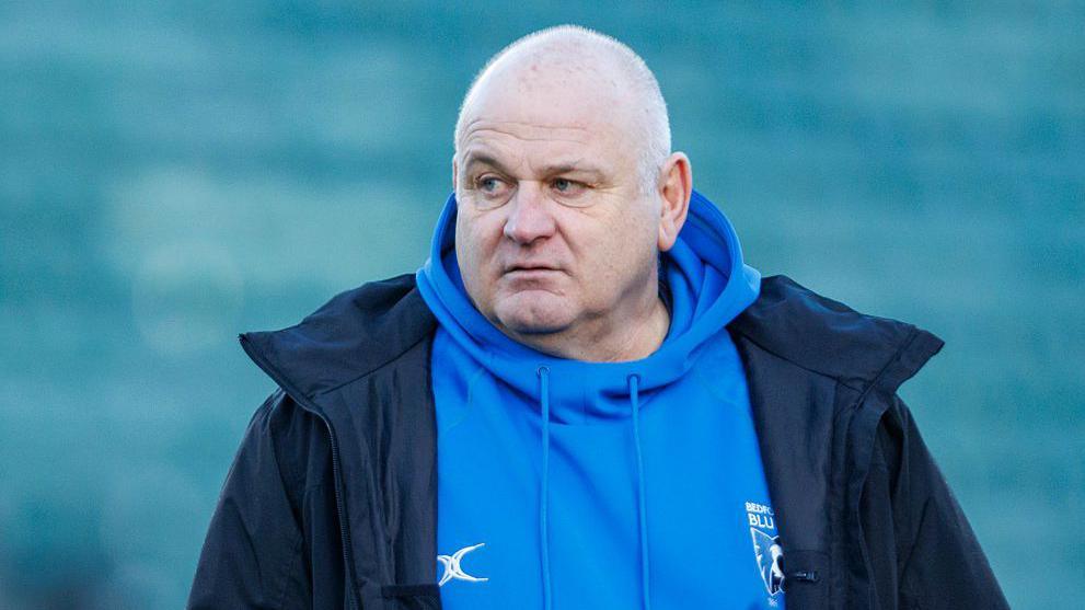 Bedford Blues coach Mike Rayer in a navy coat and a blue Bedford Blues hoodie.