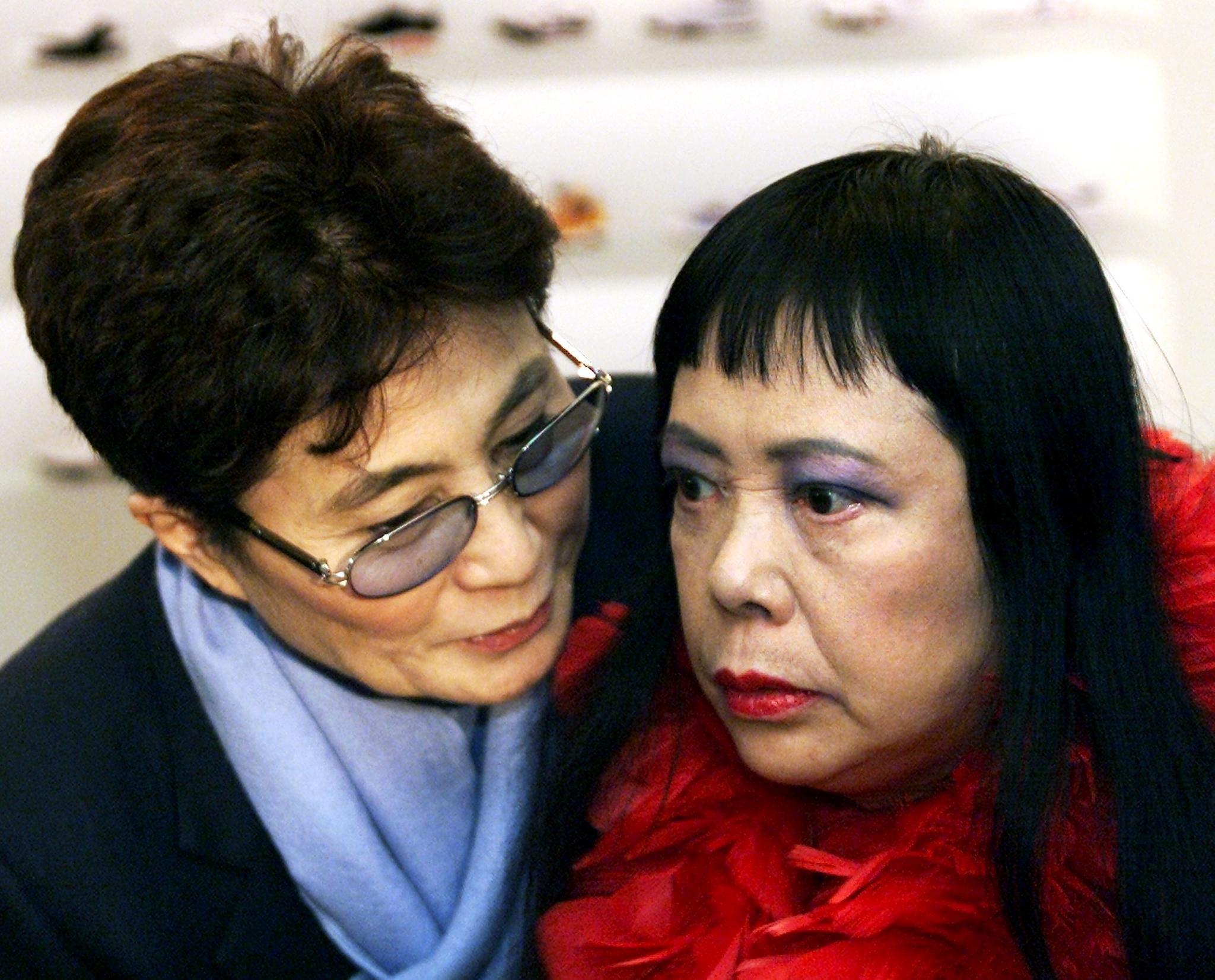 Yoko Ono leaning and speaking to Yayoi Kusama in 2000