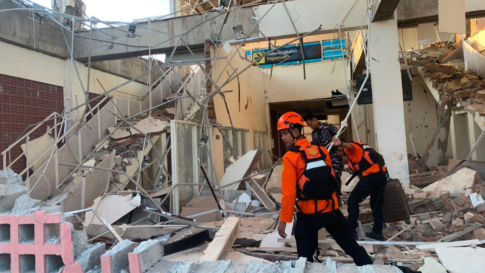 Emergency workers look through the rubble at Lauren Say port in Maumere