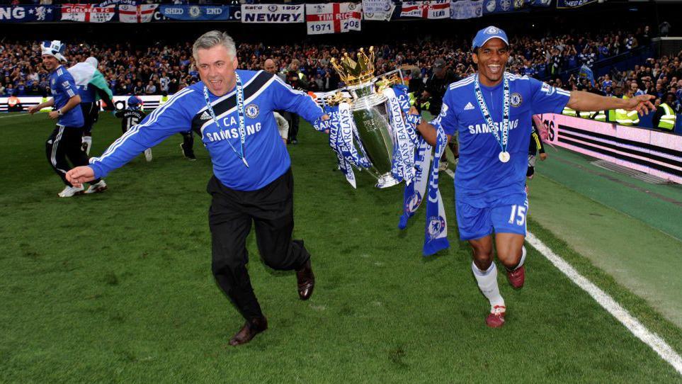 Carlo Ancelotti celebrates winning the Premier League title with the trophy