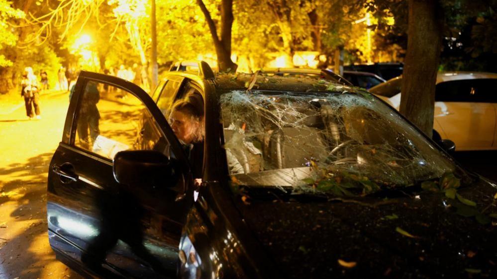 Firefighters work at the site of an apartment building hit by a Russian missile strike in Kyiv
