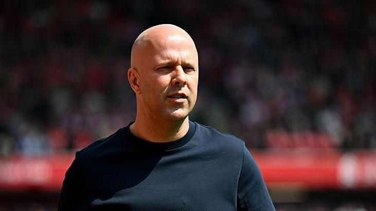 Arne Slot is looking on while wearing a black top