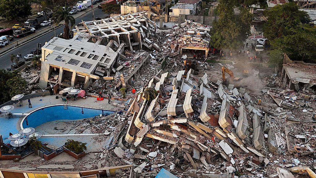 The wreckage of crumbled apartment blocks sprawl across the ground.