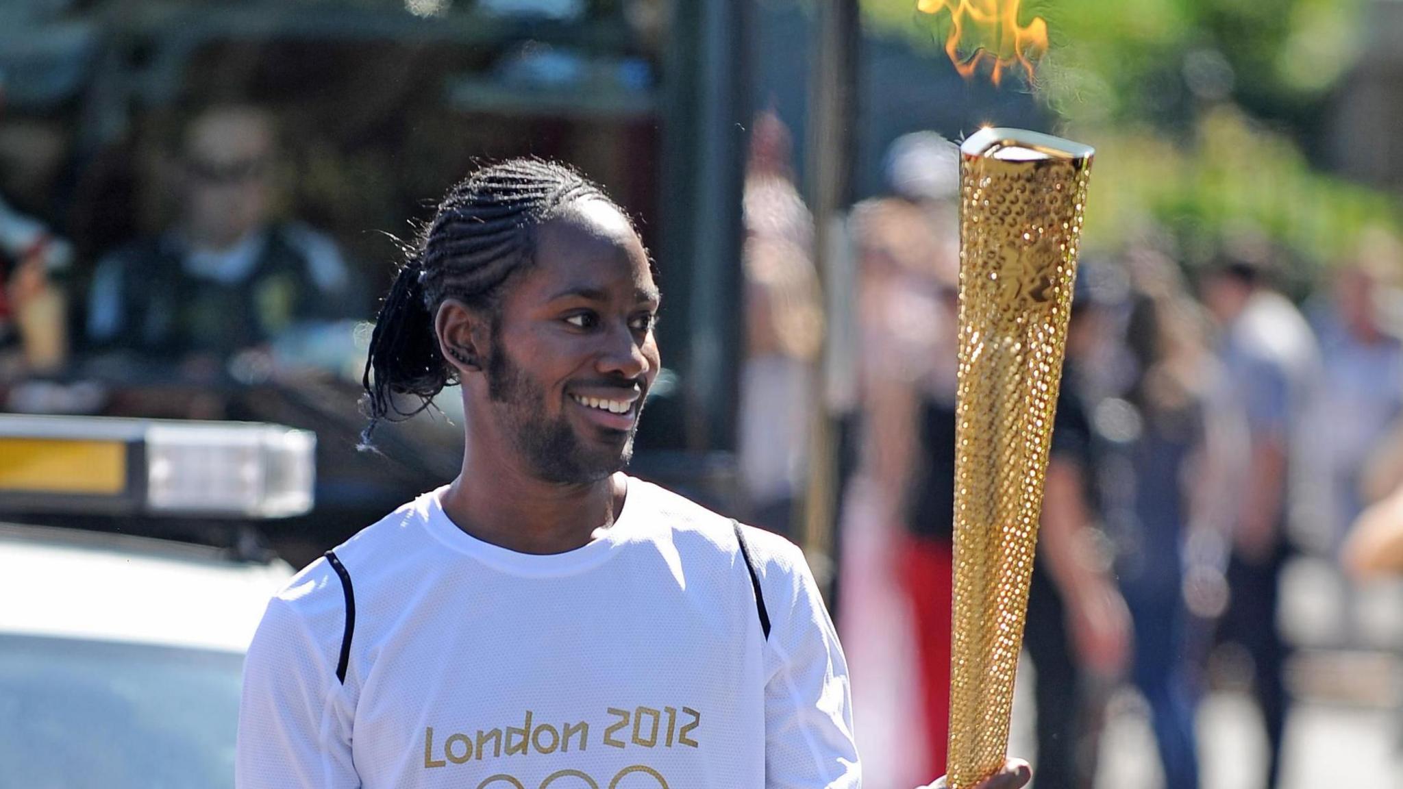 ason Arday carries the Olympic Flame on the Torch Relay leg between Sutton (London Borough) and Merton (London Borough)