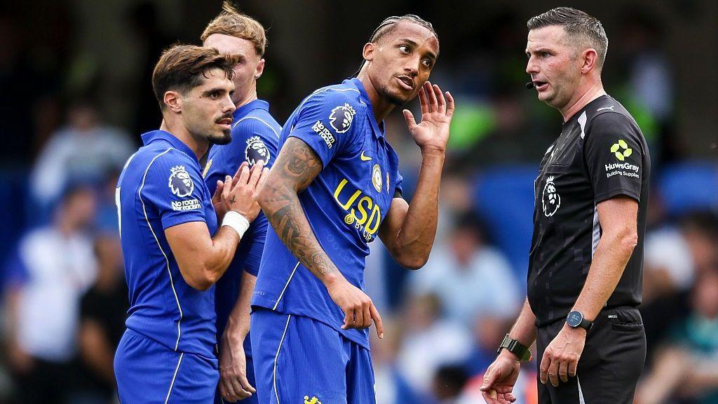 Joao Pedro of Chelsea shows referee Michael Oliver a head injury after a challenge from Lewis Dunk of Brighton & Hove Albion