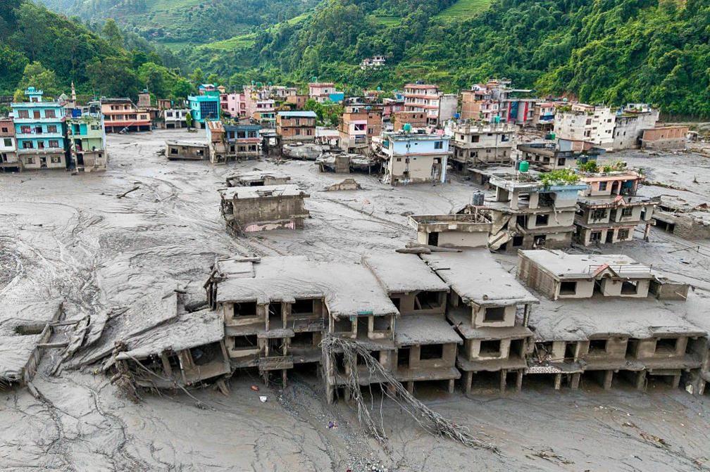 An aerial view shows houses lying deluged in sludge after flash floods at Devighat, Bidur Municipality in Nepal's Nuwakot district on August 27, 2026. Nepal's disaster agency said that 823 people remained out of contact on August 27, more than 24 hours after a deadly flood tore through the border region with Tibet. (Photo by Prabin RANABHAT / AFP via Getty Images)