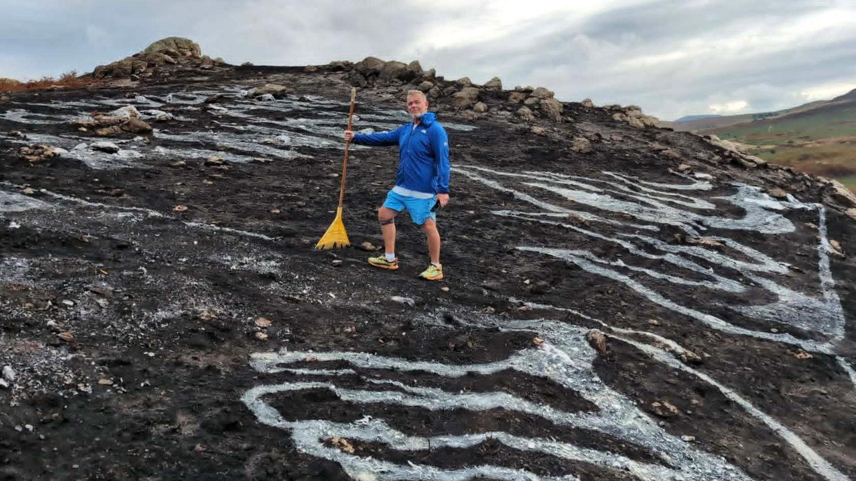 Dean Saunders in a blue top and blue shorts on a blackened mountain in yellow trainers