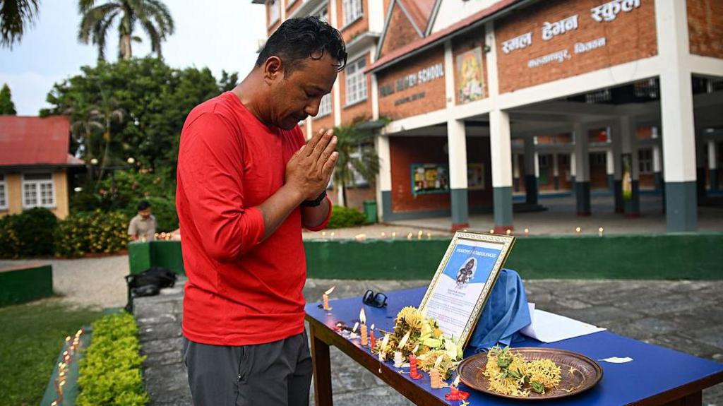 A man wearing a red shirt offering his condolences