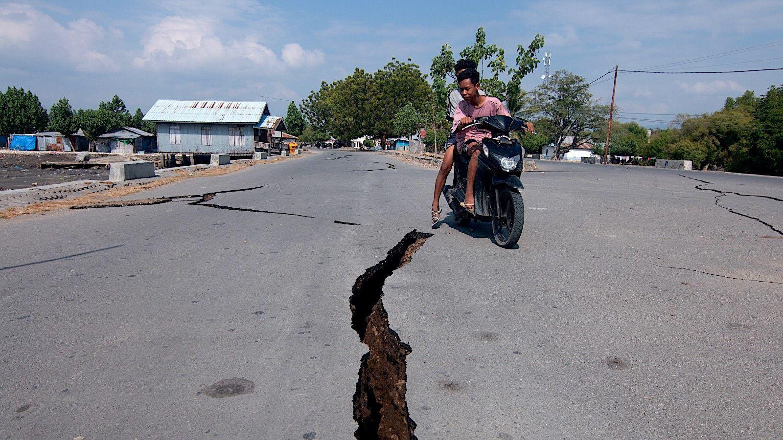 A motorcyclist rides past a crack on the road following the earthquake in East Nusa Tenggara Province, Indonesia.