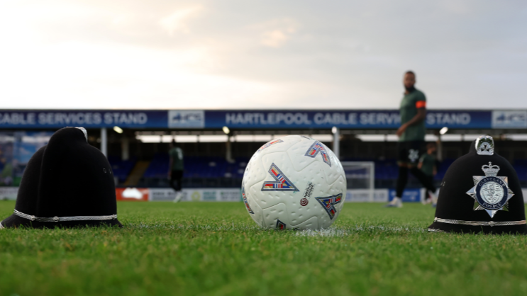 A football ball is on the place on the football pitch between two police helmets ahead of Hartlepool United's game against Eastleigh on Friday.