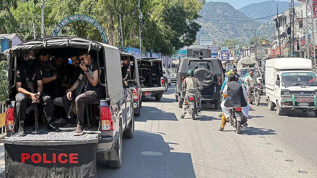 Security personnel in a police vehicle patrol a busy road in Muzaffarabad