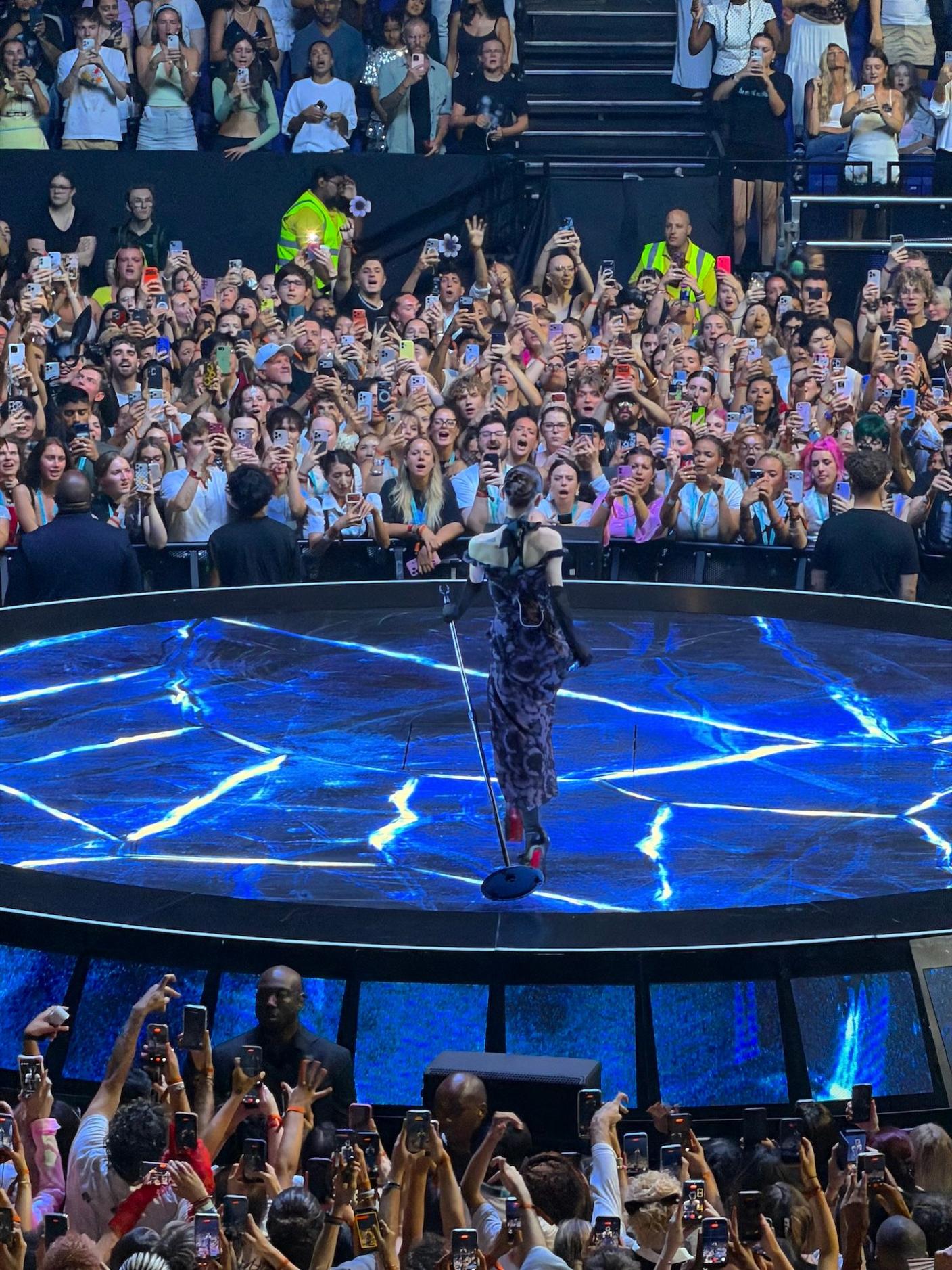 Ariana Grande on stage at the O2. Her back is to the camera and you can see audience members trying to take her photo on the opposite side of the arena