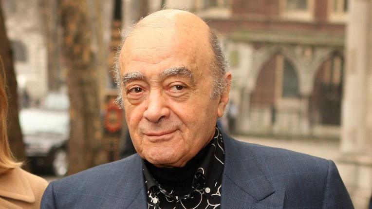 Harrods owner Mohamed Al Fayed wearing a suit and black shirt