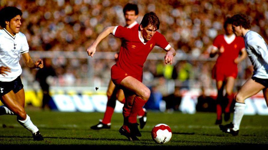 Kenny Dalglish runs with the ball at his feet in Liverpool's red kit