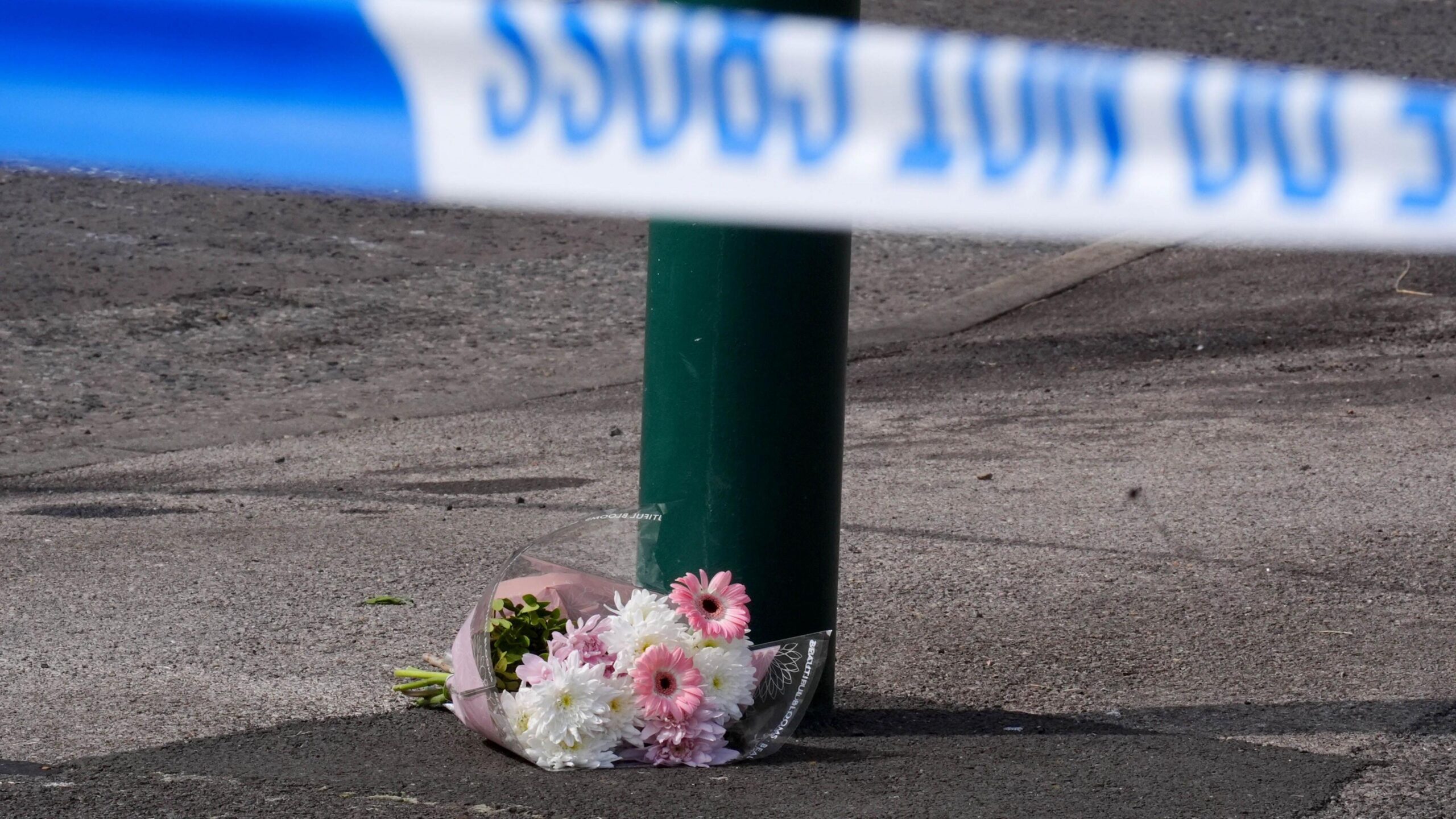 A floral tribute left near the scene, where a murder investigation has been launched after two people died in a house fire at a property in Grangetown, near Middlesbrough. A bouquet of pink and white flowers lies next to a lamppost, with a police tape in front of it