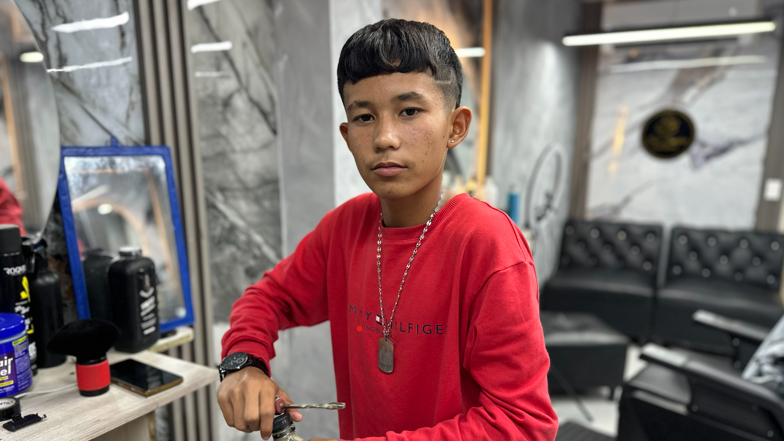 A teenage boy looks into the camera while opening the threaded top of a bottle.