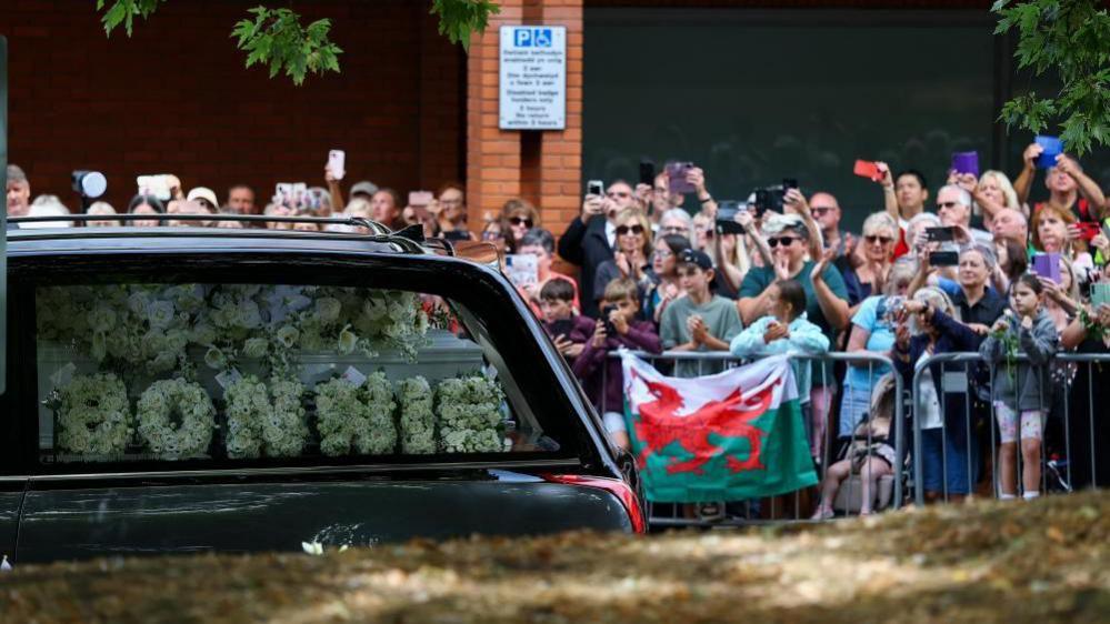 Crowds line the street as the funeral cortege passes.