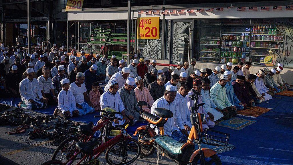 SELANGOR, MALAYSIA - JUNE 07: Rohingya Muslims gather and pray in front of a wholesale market during Eid al-Adha on June 07, 2025 in Selangor, Malaysia. Among those participating are Rohingya refugees who, despite facing legal and social challenges, continue to uphold their cultural and religious practices in Malaysia, including the observance of Islamic festivals as part of their faith. Eid al-Adha, also known as the "Festival of Sacrifice," commemorates Prophet Ibrahim's willingness to sacrifice his son in obedience to God, a devotion honored through the ritual slaughter of livestock, with the meat distributed among family, friends, and those in need. (Photo by Annice Lyn/Getty Images)
