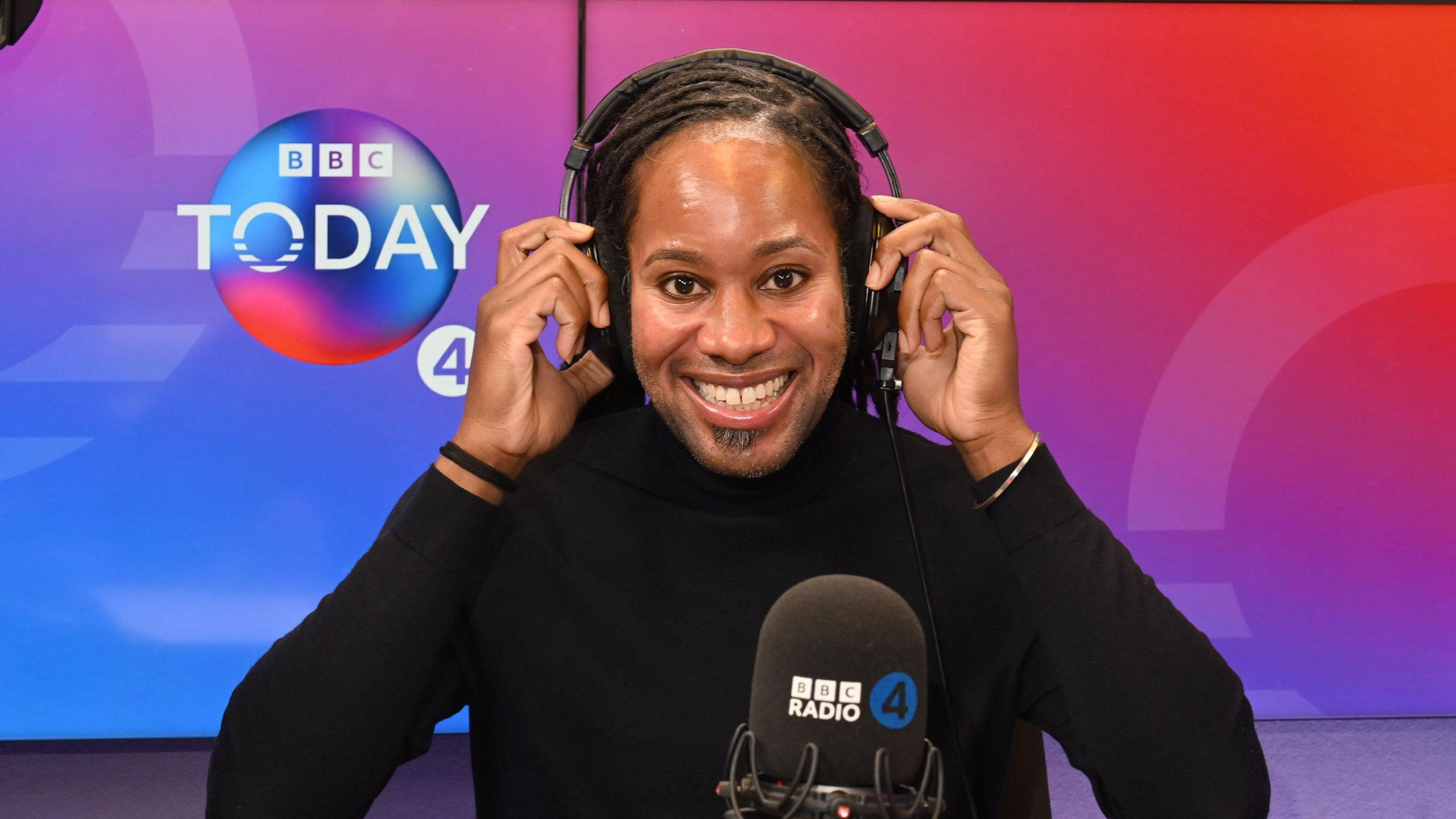 Jason Arday holds his headphones as he smiles at the camera on the set of BBC Radio 4 Today