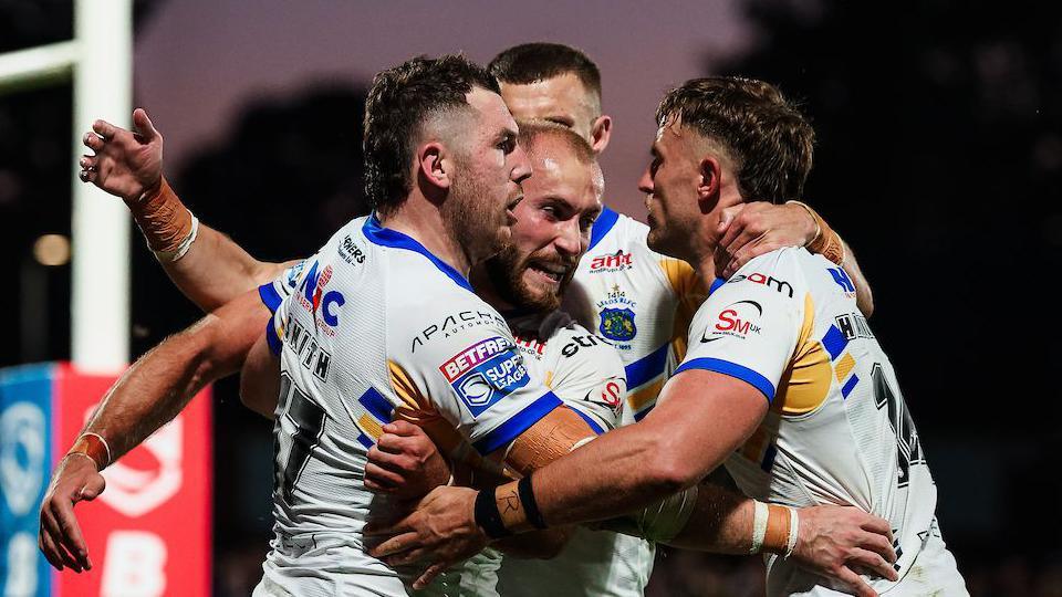 Leeds Rhinos players in white shirts celebrate a try