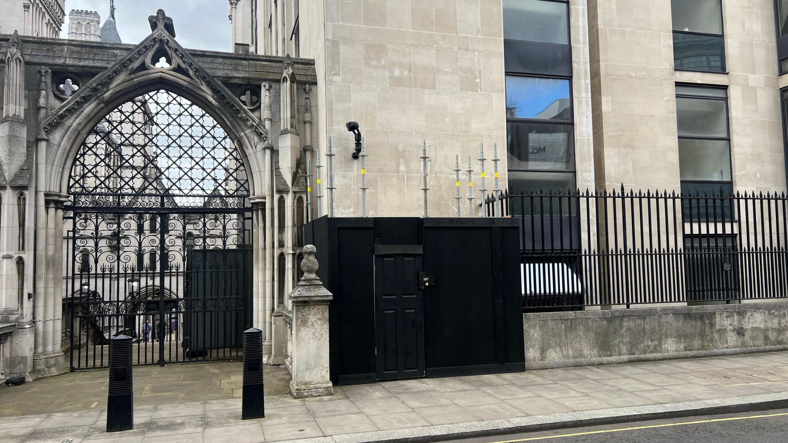 Black-painted, wooden boxing with a locked doorway around a section of wall of the Royal Courts of Justice, which was painted with a mural by Banksy.