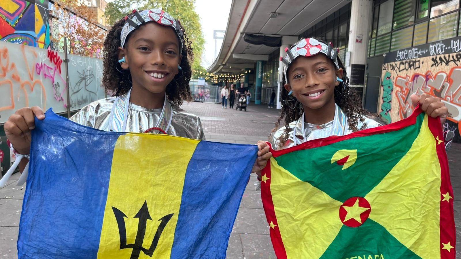 Two boys hold flags and smile at the camera