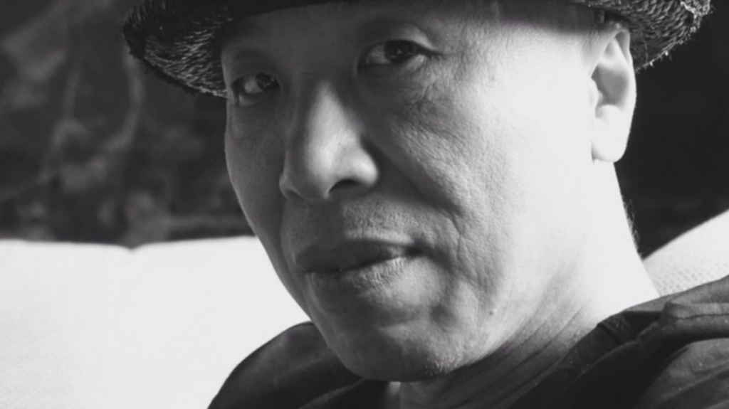 Black and white image of Gao Zhen wearing a hat and looking at the camera