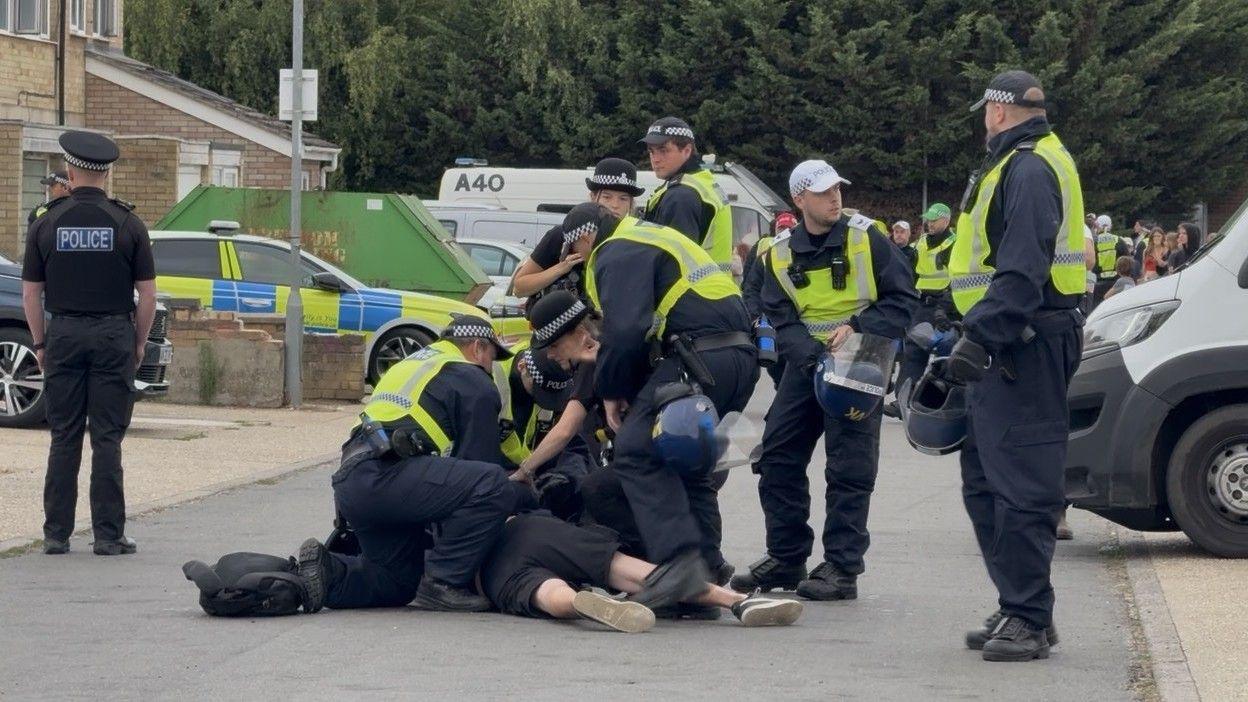 A group of police around a man being arrested on the ground.