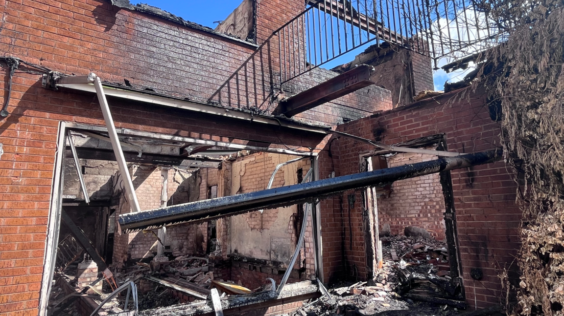 A fire damaged building with windows missing, collapsed beams and blackened walls