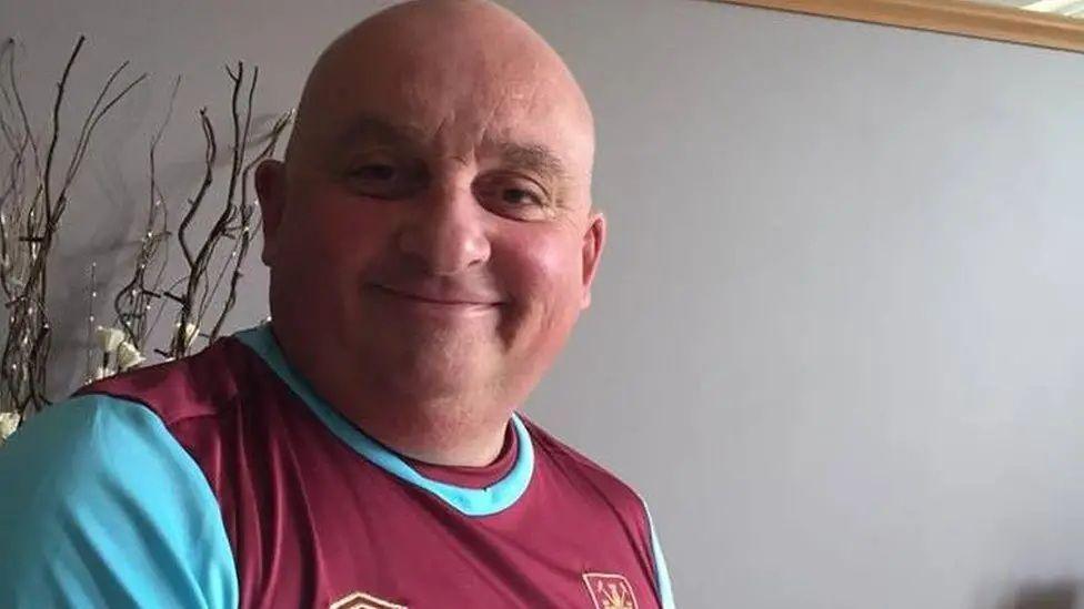 A picture of Mick Ferris in a West Ham T-shirt. He is a bald man with a ruddy complexion