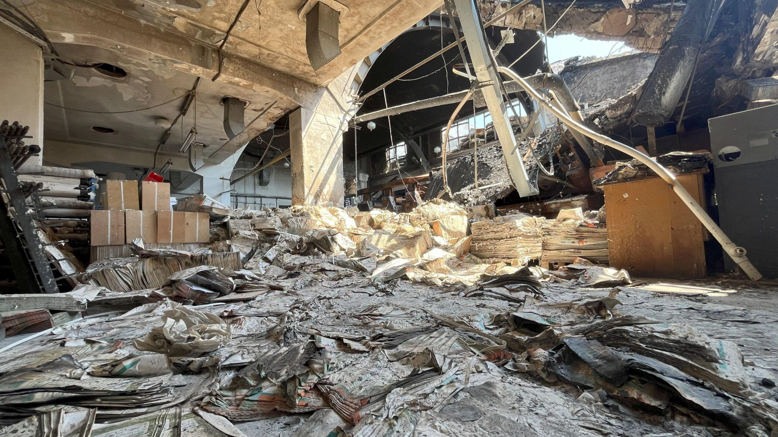 A bombed-out warehouse. Floor is littered with textbooks and detritus.