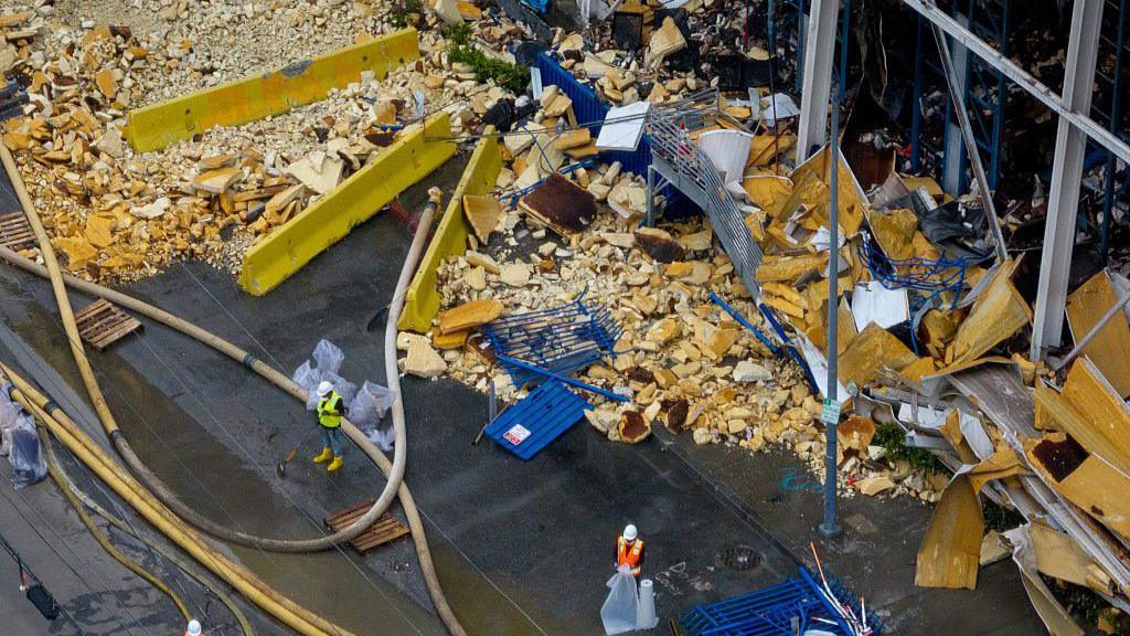 An aerial shot of construction crews trying to clean up heaps of rotting debris