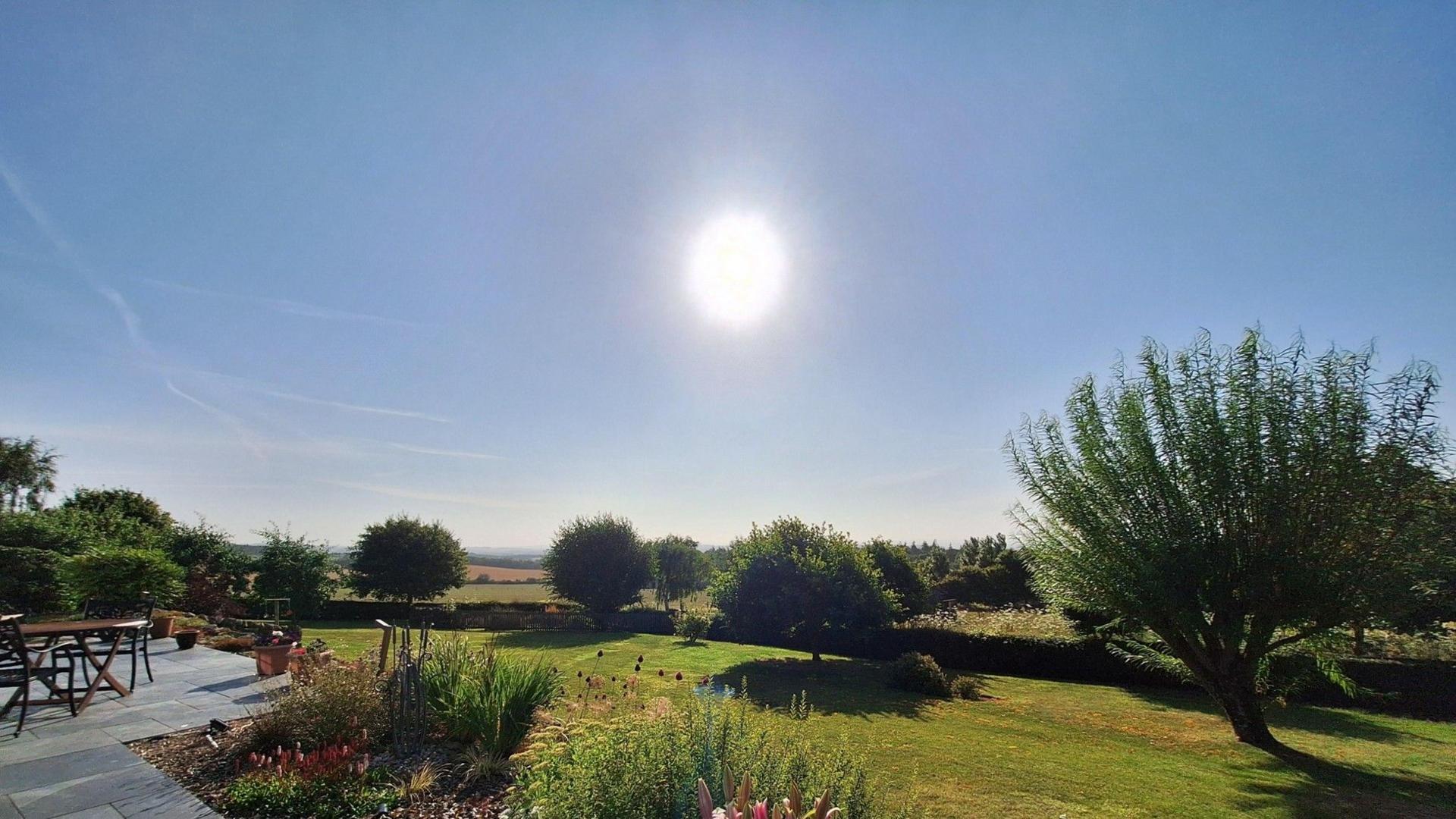 Sunny landscaped garden with flowers, lawn and countryside views in Bowden, The Scottish Borders