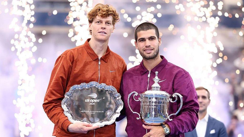 Spain's Carlos Alcaraz and Italy's Jannik Sinner pose with their trophies after Alcaraz won the 2025 US Open men's singles final