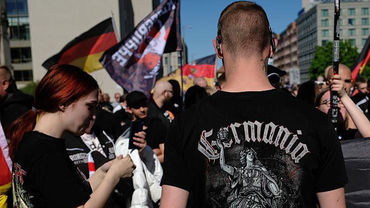Young neo-Nazis with German flags, including one young man with a black t-shirt that reads: "Germania", wait to be allowed by police to resume a demonstration in Berlin last year.