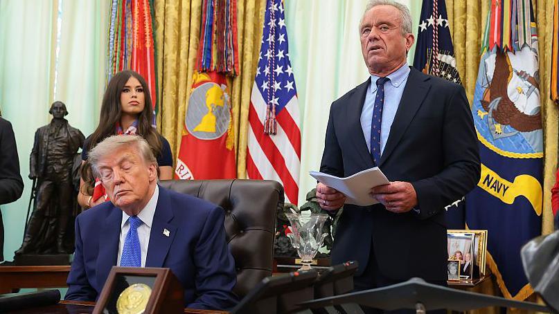 Health and Human Services Secretary Robert F. Kennedy Jr. (2nd-R), accompanied by (L-R) National Institutes of Health Director Jay Bhattacharya, U.S. President Donald Trump, Jayme Leagh Franklin with the The Conservateur, and Deputy Assistant to the President for Domestic Policy Dr. Heidi Overton (R), speaks before Trump signs an executive order calling for childhood vaccine shots to be spaced out into separate visits during an event in the Oval Office of the White House on August 10, 2026 in Washington, DC.