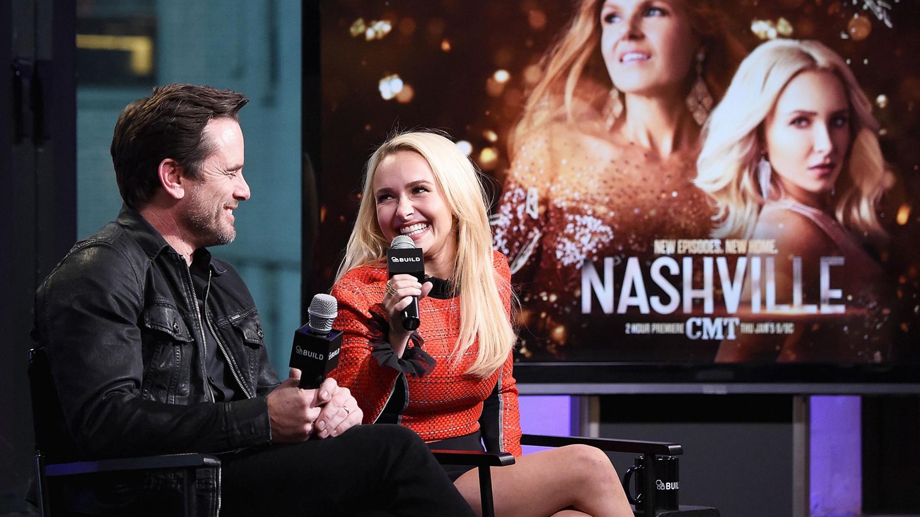 Charles Esten and Hayden Panettiere at a press event with a "Nashville" poster behind them