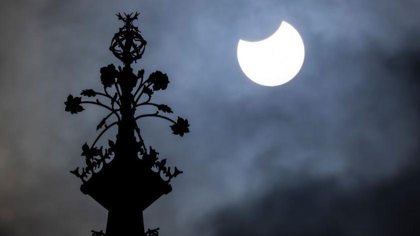 People watch the sky from Primrose Hill in north London as photographers aim cameras towards the horizon.